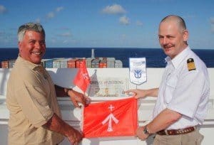 Dr. Peer Schmidt-Walther überreicht Kapitän Udo Wülms im Indischen Ozean Flagge und Ostsee-Zeitung auf der Brücke