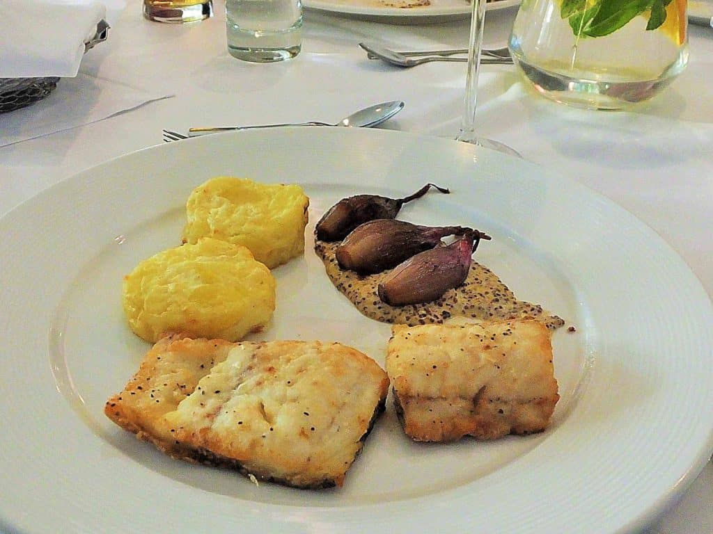 Zu den Fischgerichten im Restaurant "Brasserie" gehört auch Gebratener Dorsch, serviert auf Kartoffelgratin, dazu gebratene Zwiebeln und Senfsoße.